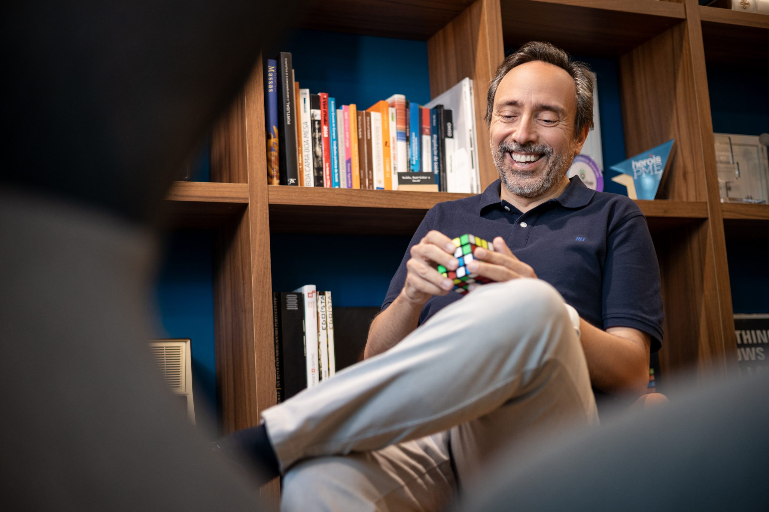 Massimo Forte, influenceur du marché immobilier, assis dans sa bibliothèque jouant avec un Rubik's cube
